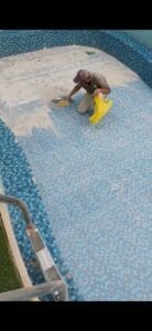 عامل ينظف بلاط أرضية المسبح.
